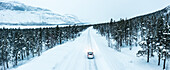 Overhead car-view driving on icy road crossing a forest covered with snow, Stora Sjofallet, Norrbotten County, Lapland, Sweden, Scandinavia, Europe