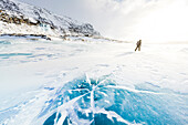 Hiker exploring the snowy landscape walking on icy lake in winter, Stora Sjofallet, Norrbotten County, Lapland, Sweden, Scandinavia, Europe