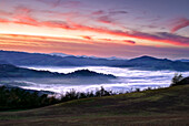 A sea of fog and low clouds in a valley at sunset, Italy, Europe