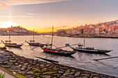 Blick auf den Douro-Fluss und die Rabelo-Boote mit den bunten Gebäuden bei Sonnenuntergang, Porto, Norte, Portugal, Europa