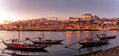 Blick auf den Douro-Fluss und die Rabelo-Boote mit bunten Gebäuden in der Abenddämmerung, Porto, Norte, Portugal, Europa