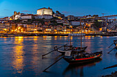 Blick auf den Douro-Fluss und die Rabelo-Boote mit bunten Gebäuden in der Abenddämmerung, Porto, Norte, Portugal, Europa