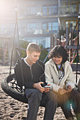 Friends using cell phone on swing