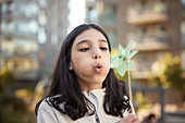 Girl blowing on pinwheel outdoors