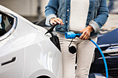 Woman charging electric car outdoors