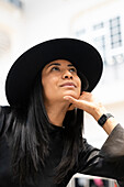 Junge Frau mit schwarzem Hut blickt nach oben