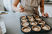 Frau in Küche bei der Zubereitung von Cupcakes