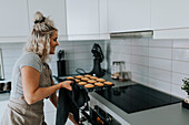 Woman in kitchen preparing cupcakes