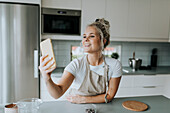 Lächelnde Frau macht Selfie in der Küche