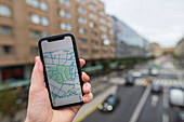 Hand holding smartphone with map app on screen