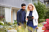 Male and female worker looking at tablet in courtyard