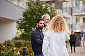 Two men and woman with laptop in courtyard