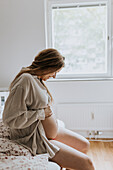 Schwangere Frau im Bett sitzend
