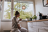 Schwangere Frau trinkt Kaffee in der Küche