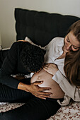 Mann küsst den Bauch seiner schwangeren Freundin