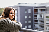 Smiling teenage girl looking at view from balcony