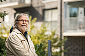 Porträt eines älteren Mannes, der in einem Wohngebiet sitzt