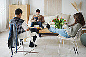 Teenager sitzen im Wohnzimmer und benutzen Handy und Tablet