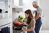 Father and daughter preparing food in kitchen