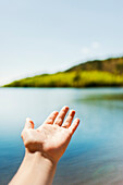 Human hand against lake