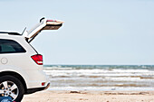 Auto mit offenem Kofferraum am Strand am Meer
