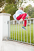 Boy jumping over fence
