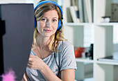 Woman using computer with headphones on