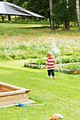 Junge spielt mit Gartenschlauch