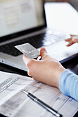 Woman holding credit card and using laptop