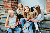 Girls sitting on steps and using cell phones