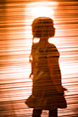 Silhouette eines Mädchens vor orangefarbenem Hintergrund