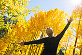 Woman with arms raised in autumn forest