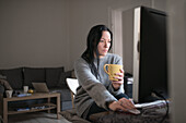 Woman holding mug, using computer