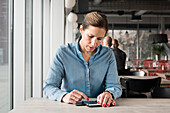 Frau im Café benutzt Mobiltelefon