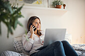 Young woman talking via phone in bed