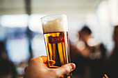 Hand hält Bier im Glas