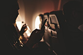 Person mit Mobiltelefon im Flugzeug