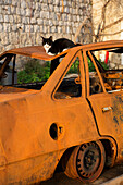 Car resting on rusty car