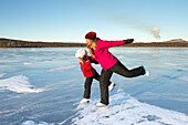 Mother and daughter ice-skating on frozen lake