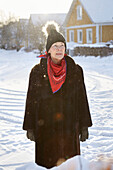 Senior woman standing in front of house in winter