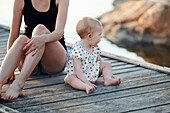 Babymädchen und Frau sitzen auf einem Pier