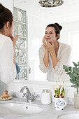 Frau im Badezimmer wäscht Gesicht