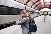 Frau auf dem Bahnsteig eines Bahnhofs