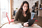 Frau mit digitalem Tablet in einem Café