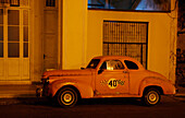 Vintage car in front of building at night