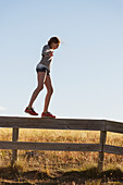 Girl walking on wooden fence