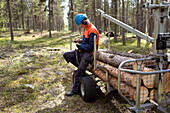 Lumberjack in forest looking at cell phone
