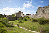 Man cycling along old ruins