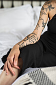 Frau mit Tattoo auf dem Bett sitzend