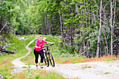 Smiling woman pushing bicycle uphill